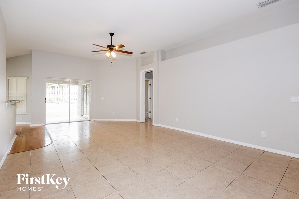 an empty living room with a ceiling fan and a tiled floor