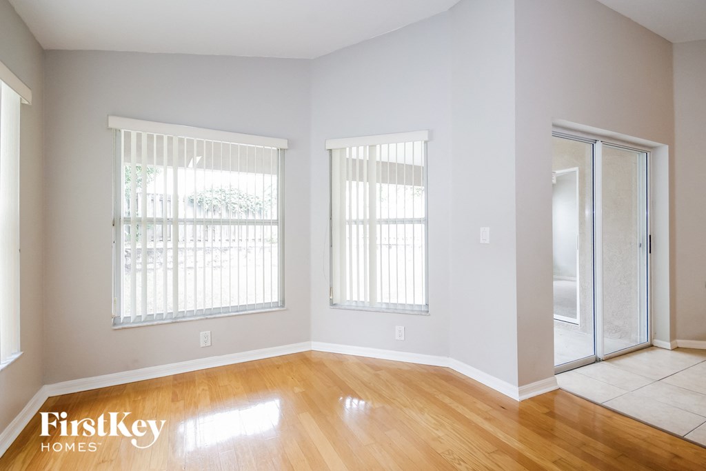 a living room with a hardwood floor and two windows