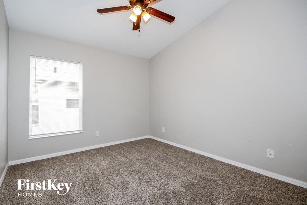 the bedroom has a carpeted floor and a ceiling fan