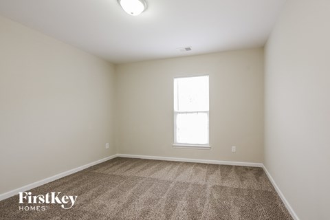 the living room of an apartment with carpet and a window