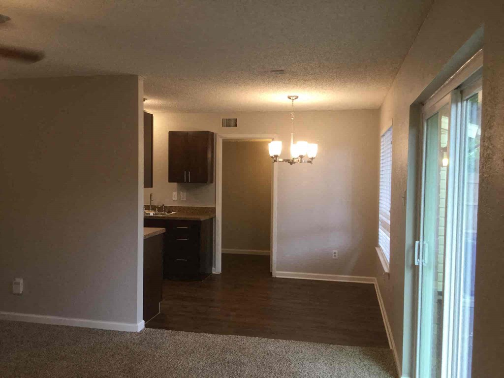 an empty living room with a door open to a kitchen