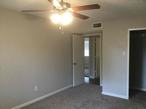 a living room with a ceiling fan and a door to a hallway