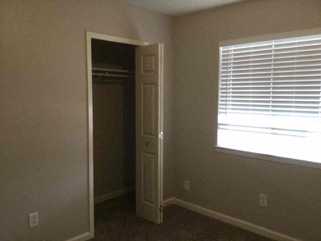 an empty room with a window and a door to a closet