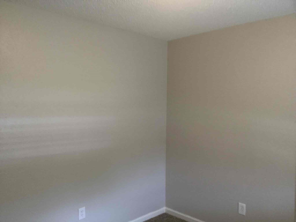 an empty room with white walls and a white electrical outlet