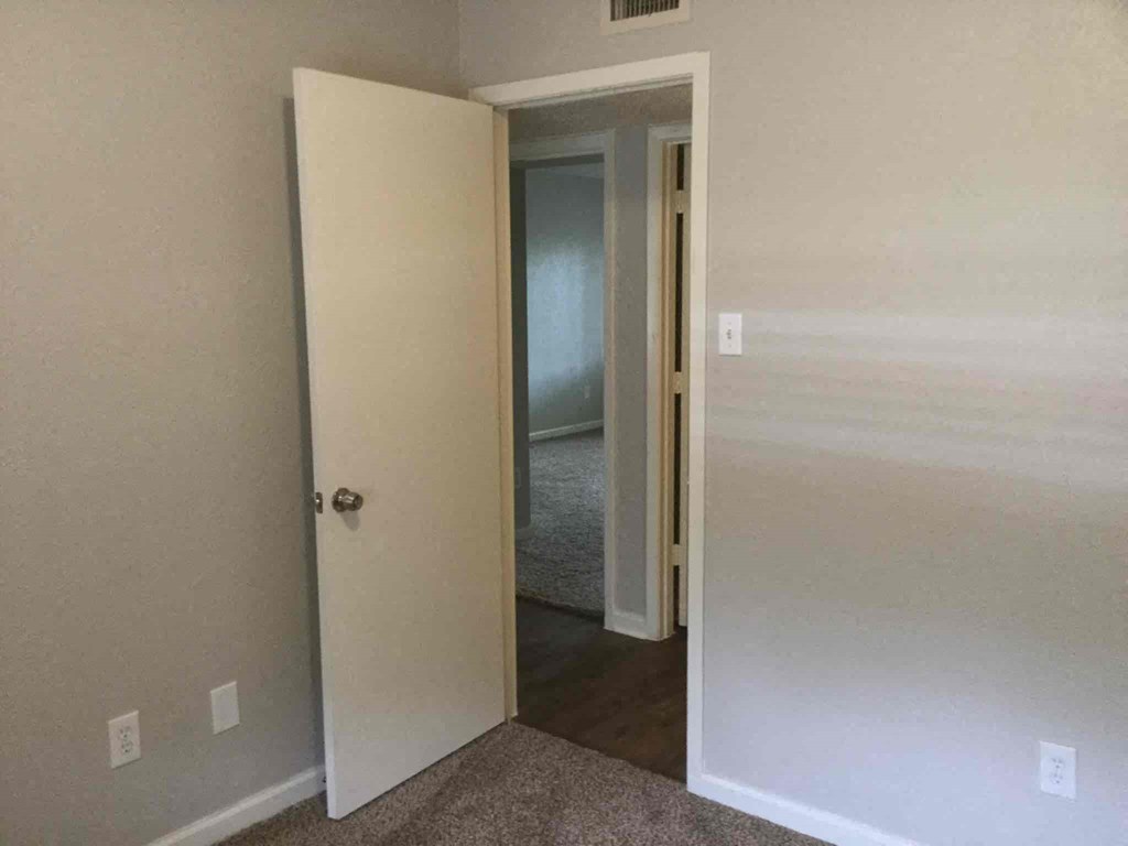 an open bedroom door with a hallway to a closet and a door to a bathroom