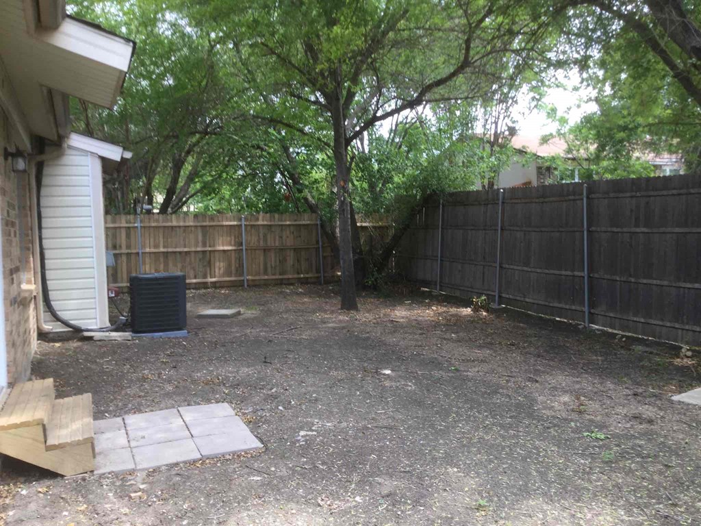 a backyard with a fence and a tree in it