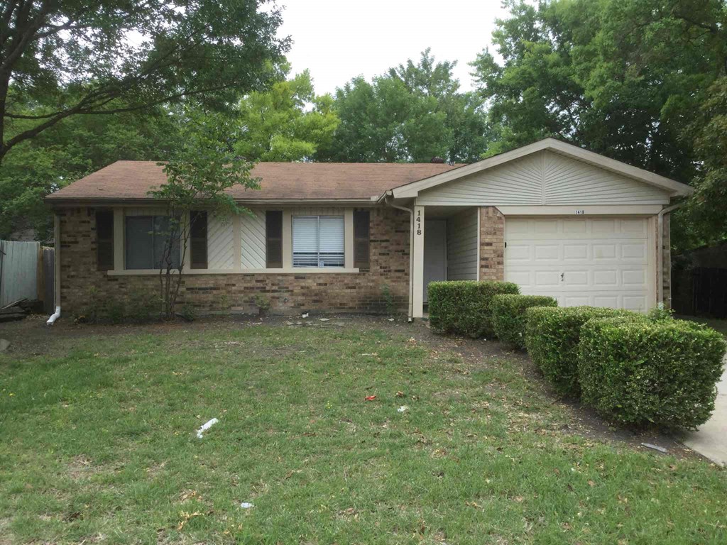 a small brick house with a lawn and bushes