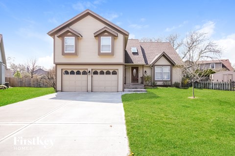 a beige house with a garage and a lawn