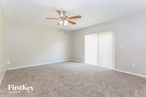 a spacious living room with carpet and a ceiling fan