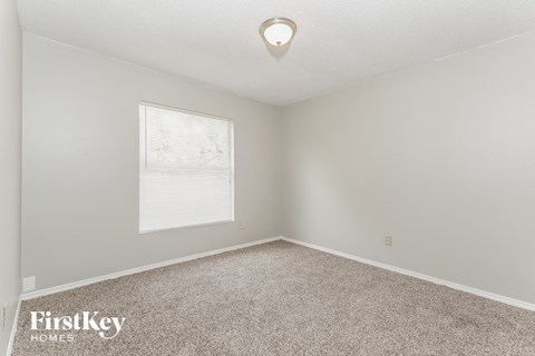 a bedroom with a large window and a carpet