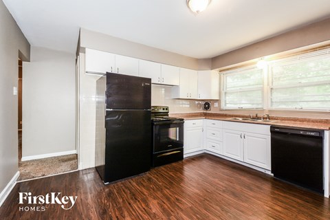A kitchen with a black fridge and white cabinets.