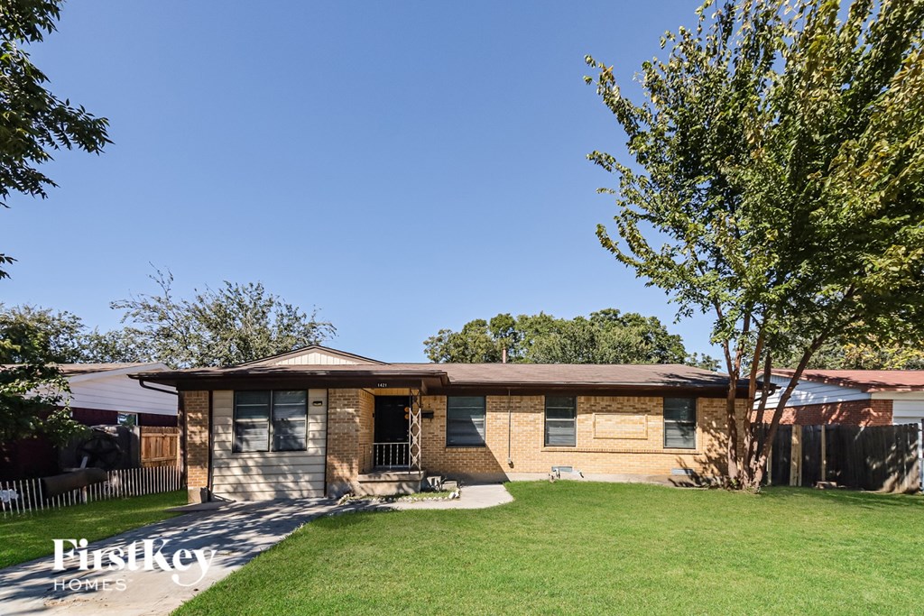 A house with a brown roof and a white fence in front.