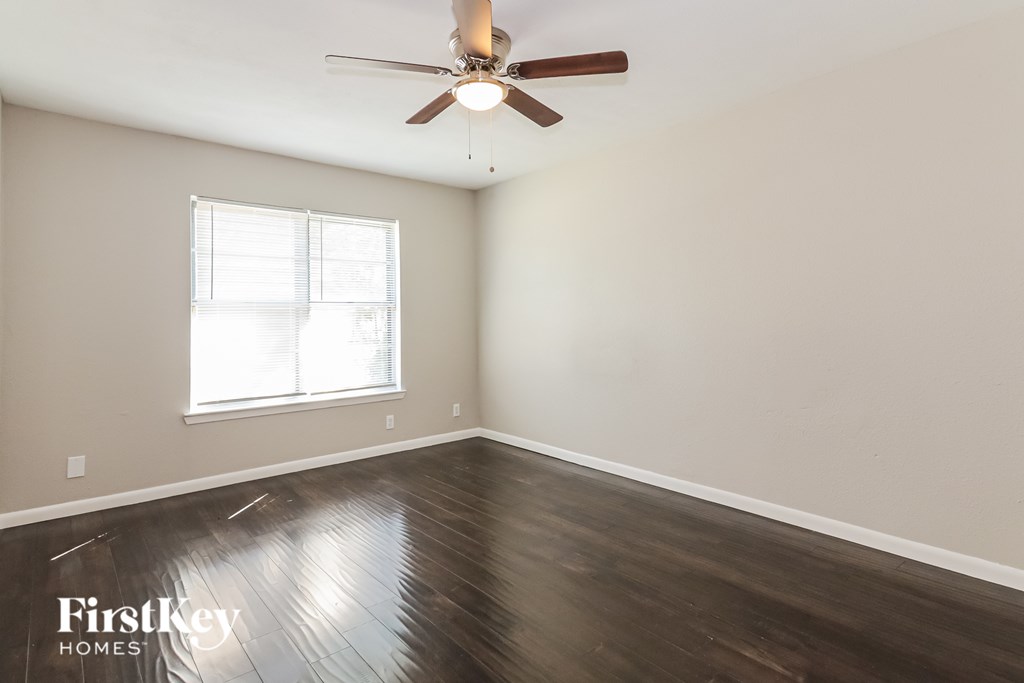 A room with a ceiling fan and wooden flooring.
