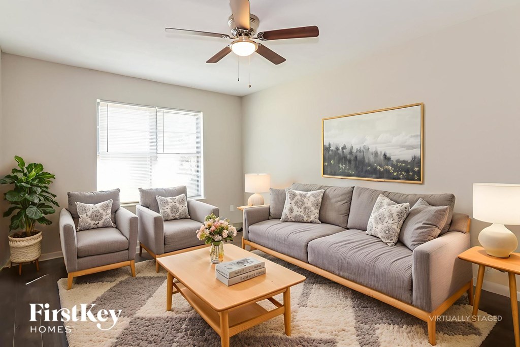 A living room with a grey couch, a wooden coffee table, and a painting on the wall.
