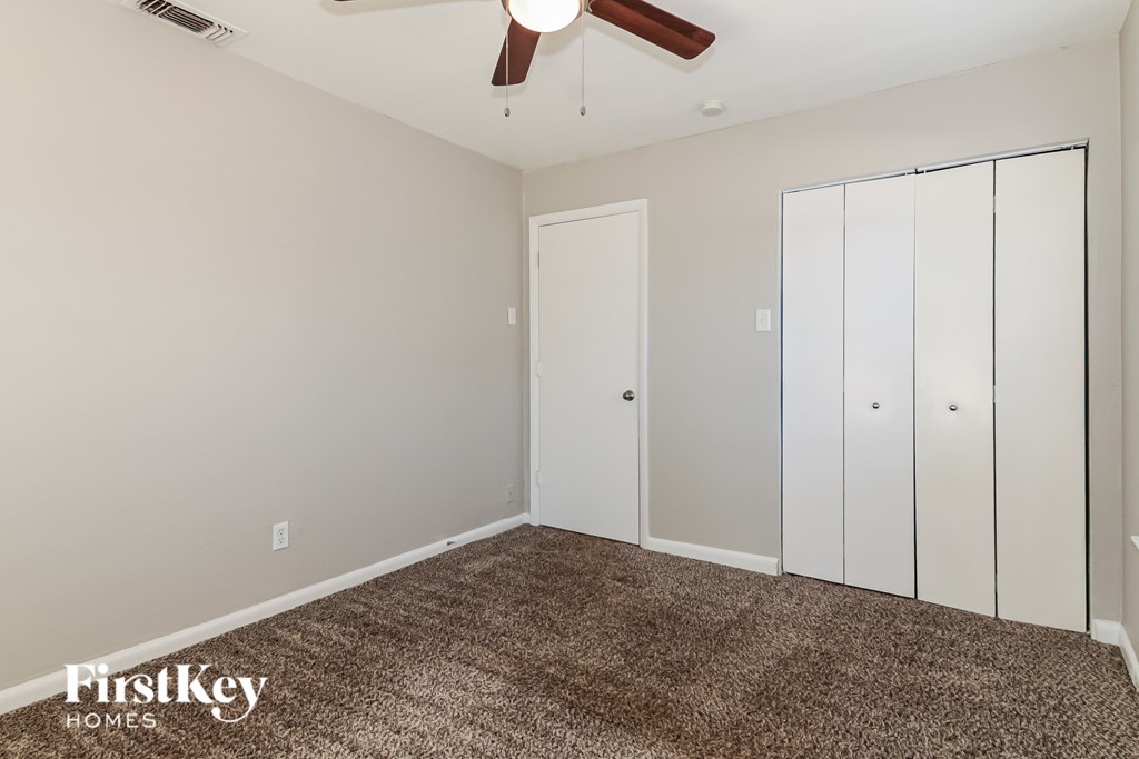 A room with a carpeted floor and a ceiling fan.
