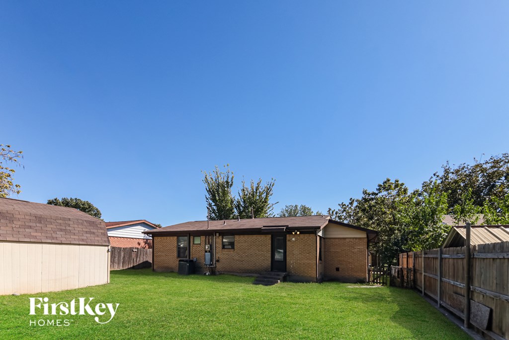 A backyard with a fence and a house.