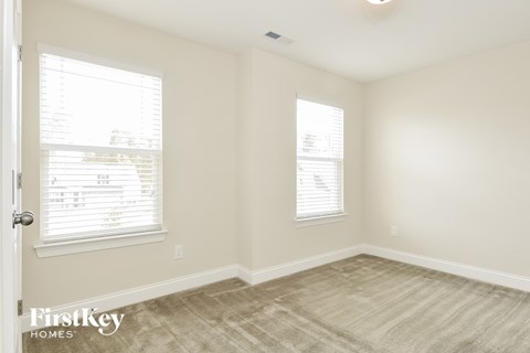 a living room with a carpet and two windows