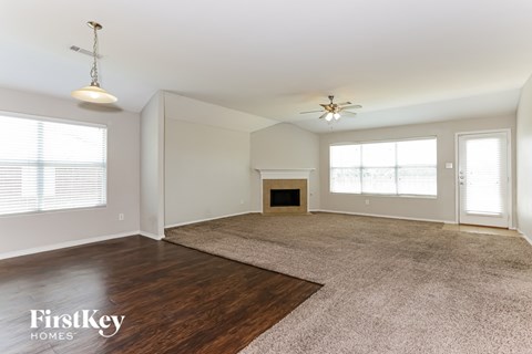 an empty living room with a fireplace and wood flooring