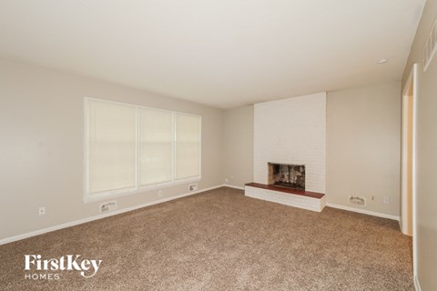 A spacious living room with a fireplace and large windows.