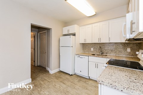 A kitchen with white cabinets and a granite countertop.