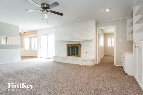 A spacious living room with a fireplace and a ceiling fan.