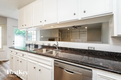 A kitchen with white cabinets and a black counter top.