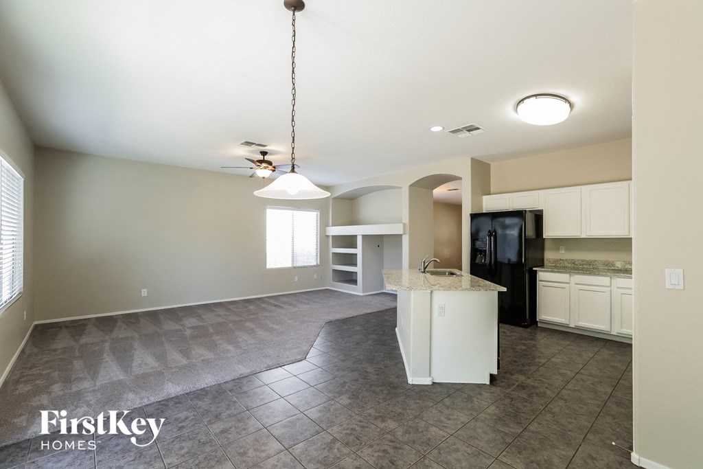 an empty kitchen with white cabinets and a black refrigerator