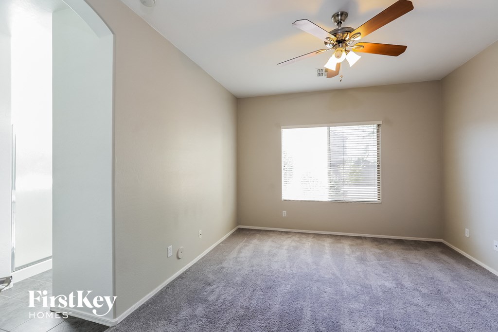 an empty living room with a ceiling fan and a window