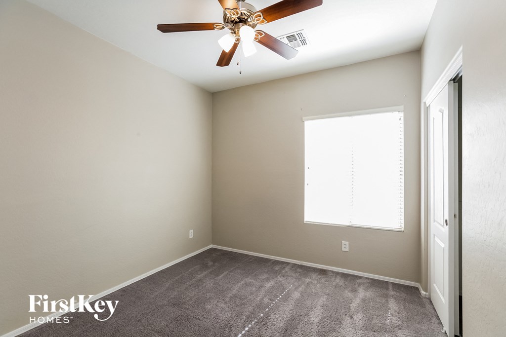an empty room with a ceiling fan and a window
