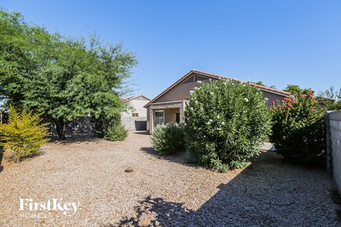 a house with a gravel driveway with trees and bushes