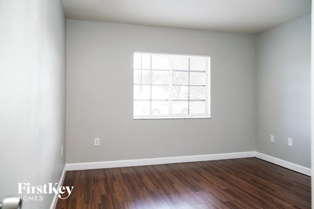 an empty room with wood floors and a window