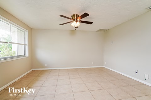 A room with a ceiling fan and tile flooring.