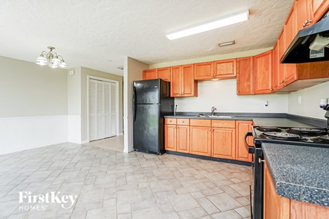 A kitchen with orange cabinets and a black fridge.