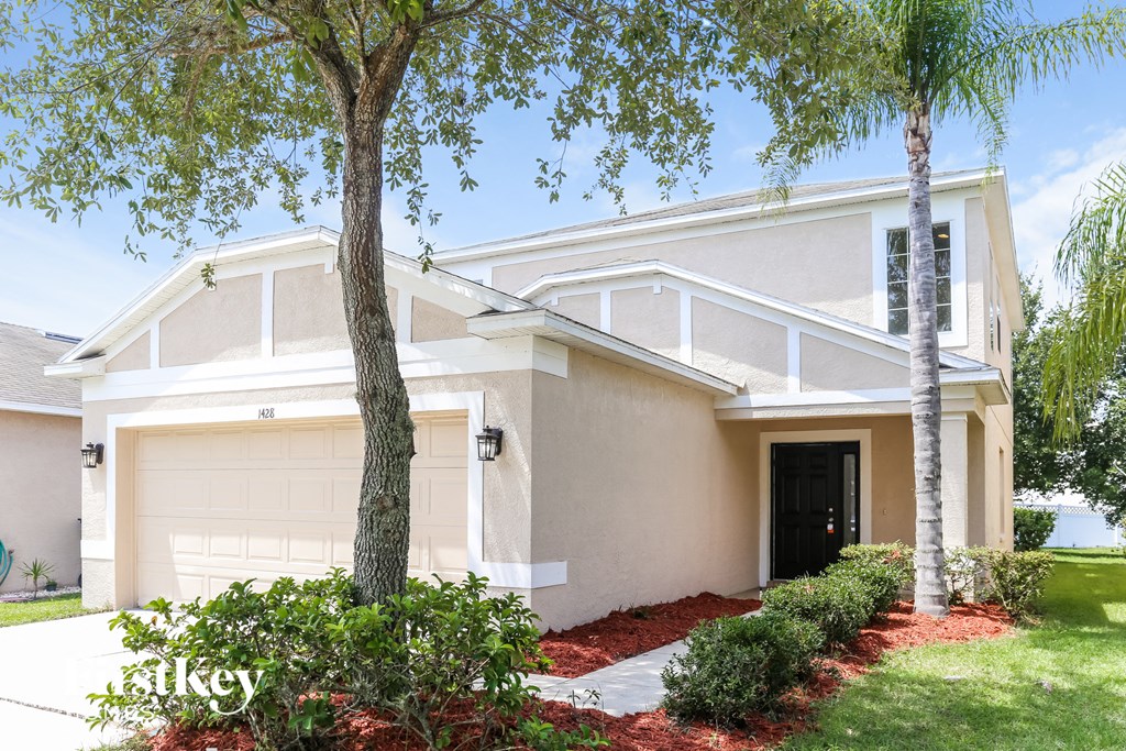 a house with a garage door and a tree