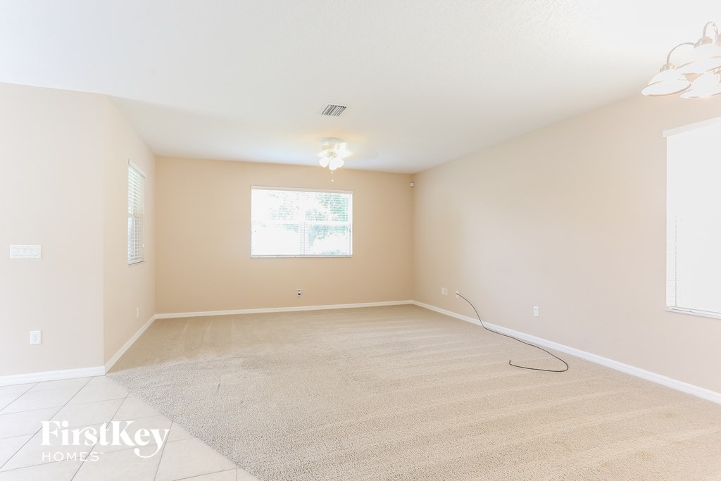a spacious living room with a carpeted floor and a window
