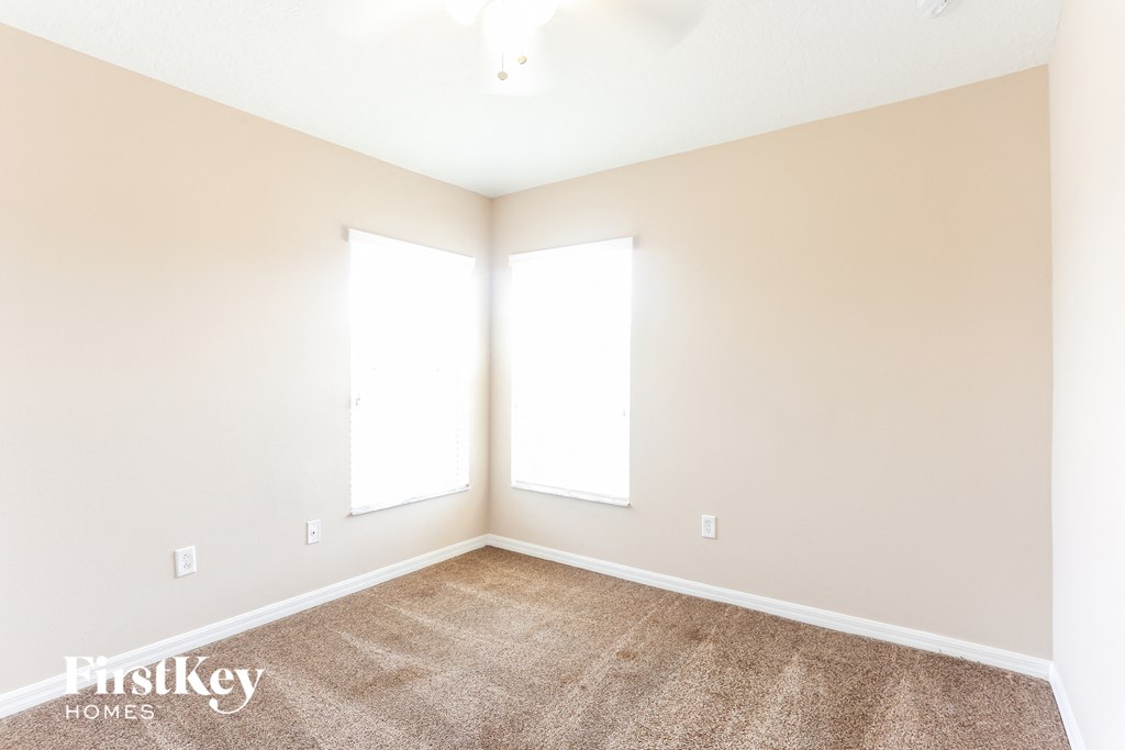 a room with carpet and two windows