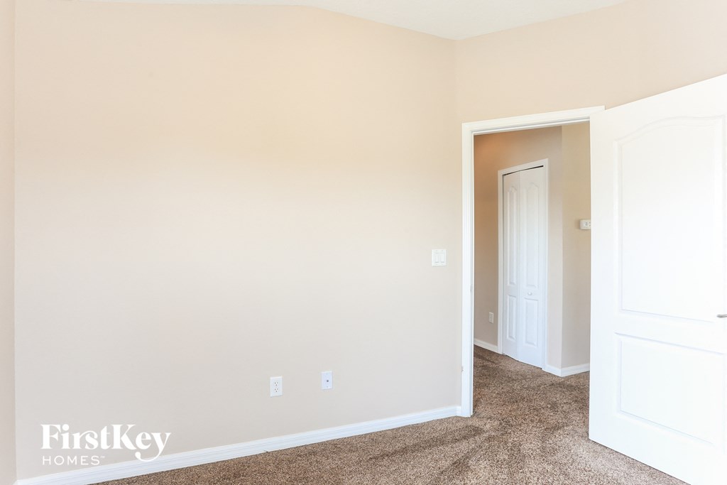 a bedroom with white walls and carpet and a door to a closet