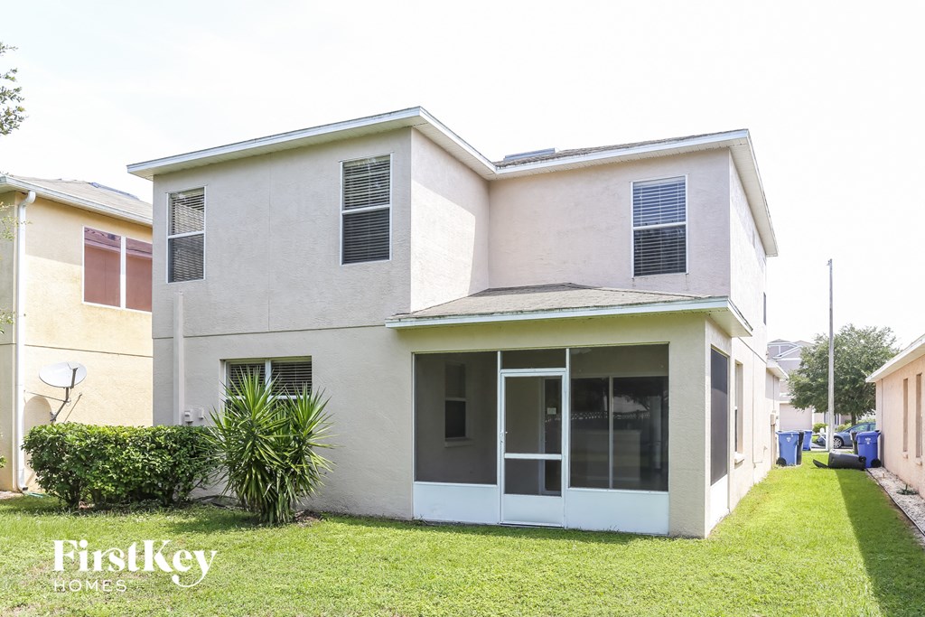 the exterior of a white house with a lawn and a palm tree