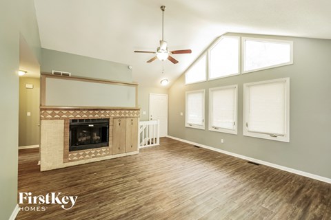 A spacious living room with a fireplace and wood flooring.