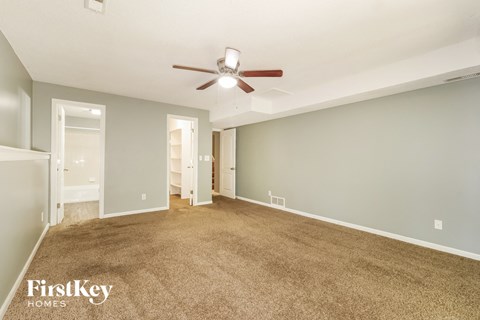 A spacious room with a carpeted floor and a ceiling fan.