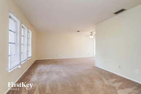 A room with a carpeted floor and a window with blinds.