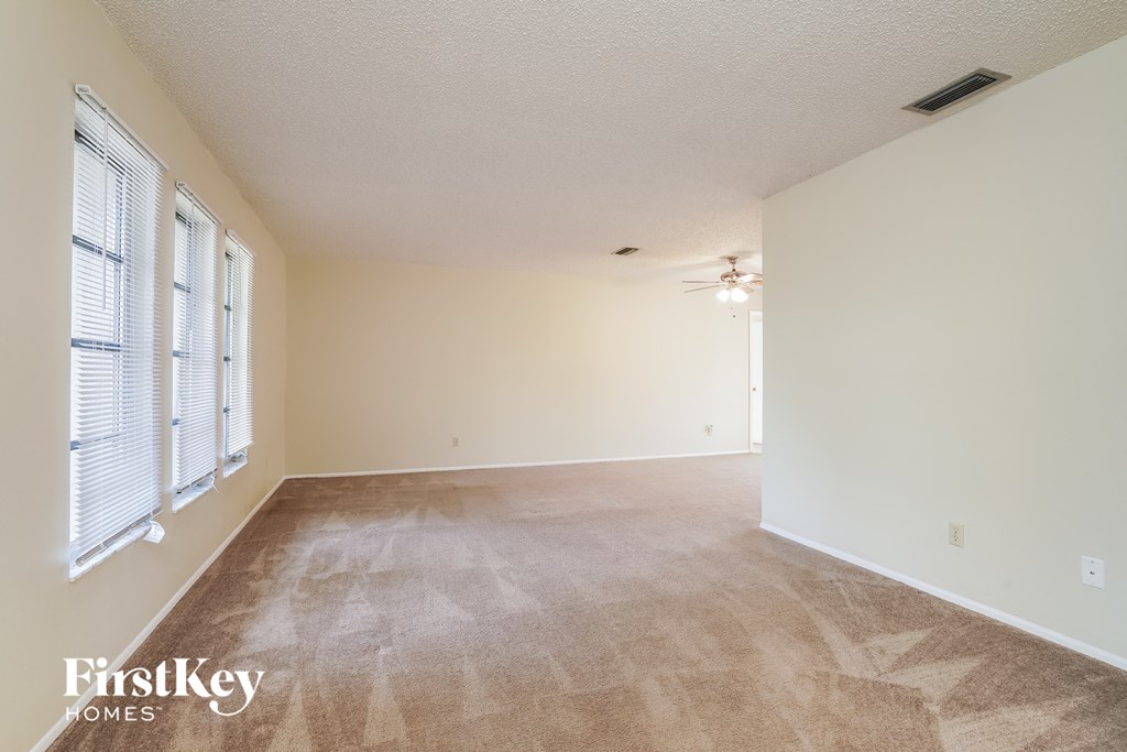 A room with a carpeted floor and a window with blinds.