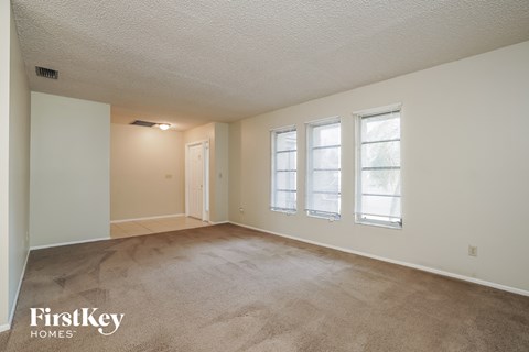 A room with a carpeted floor and a window with blinds.