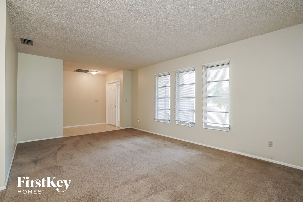 A room with a carpeted floor and a window with blinds.