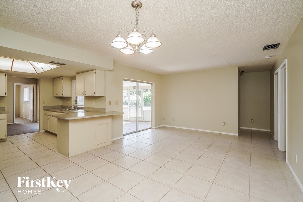 A spacious kitchen and living room with a chandelier and sliding glass doors.