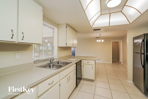 A kitchen with white cabinets and a black fridge.