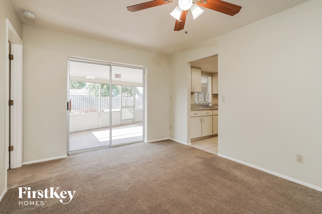 A spacious room with a carpeted floor and a ceiling fan.