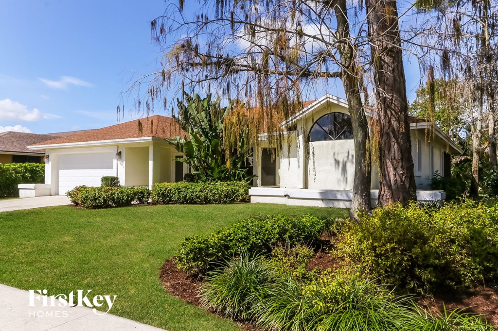 a small white house with a lawn and a tree