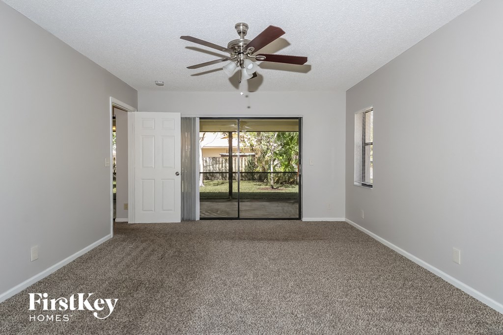 an empty living room with a ceiling fan and a door to a patio