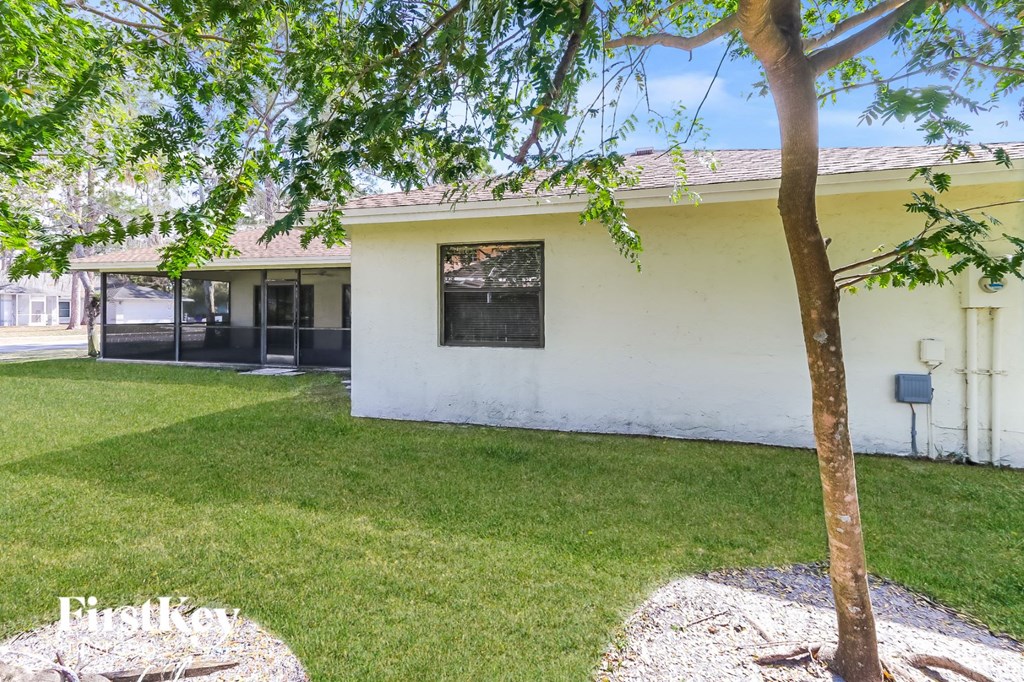 a backyard with a tree and a white house